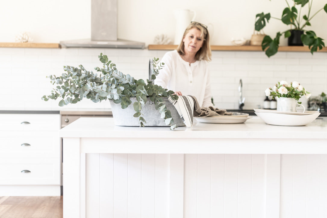 Woman in a kitchen with plants and a white countertop