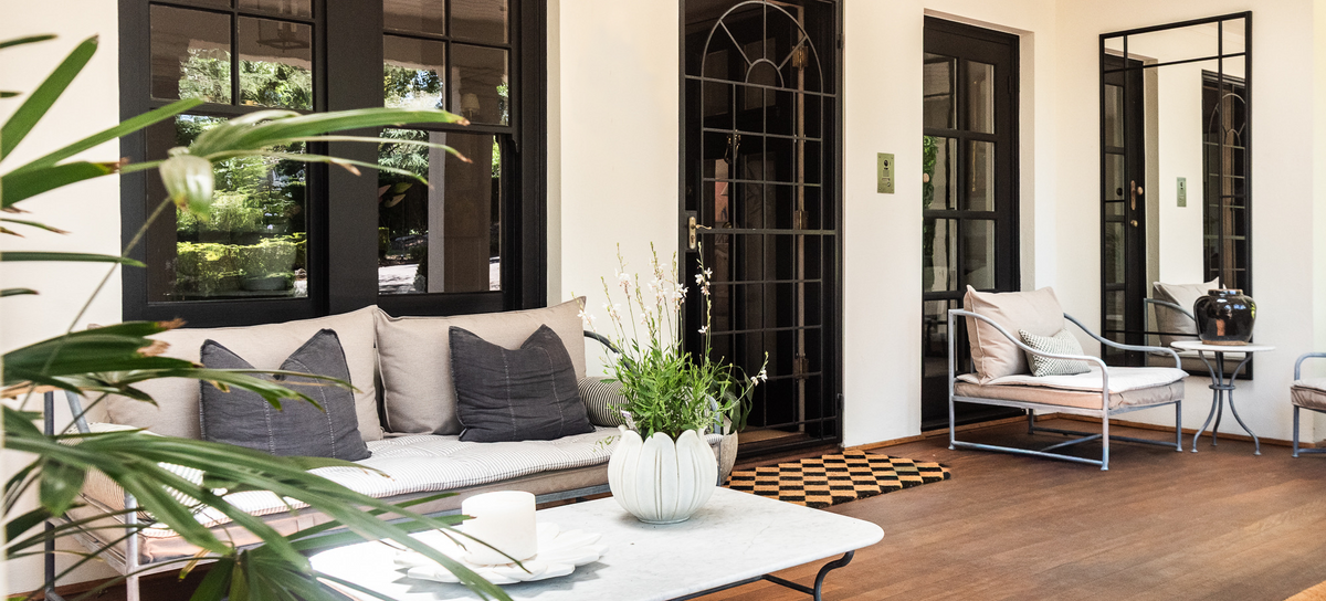 Modern living room with black-framed glass doors, white sofa, and decorative items.