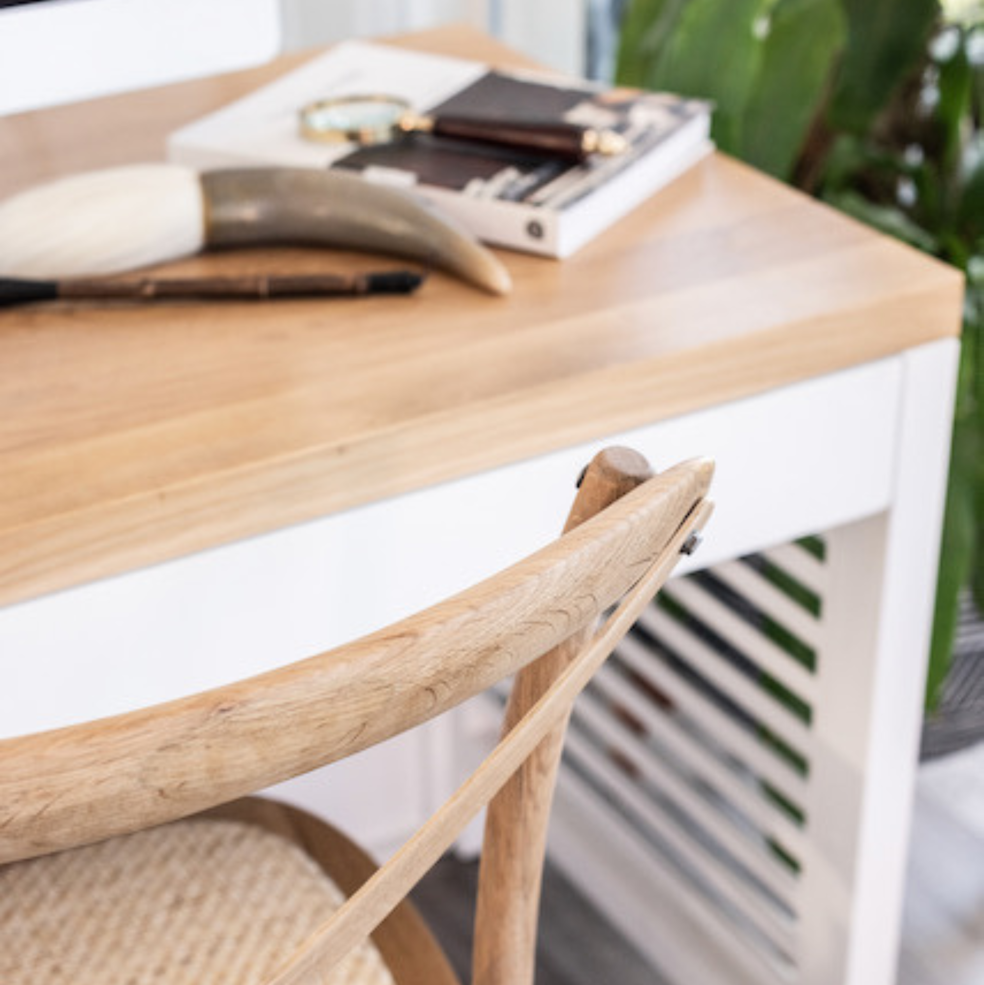 Wooden desk with a chair and items on a blurred indoor background