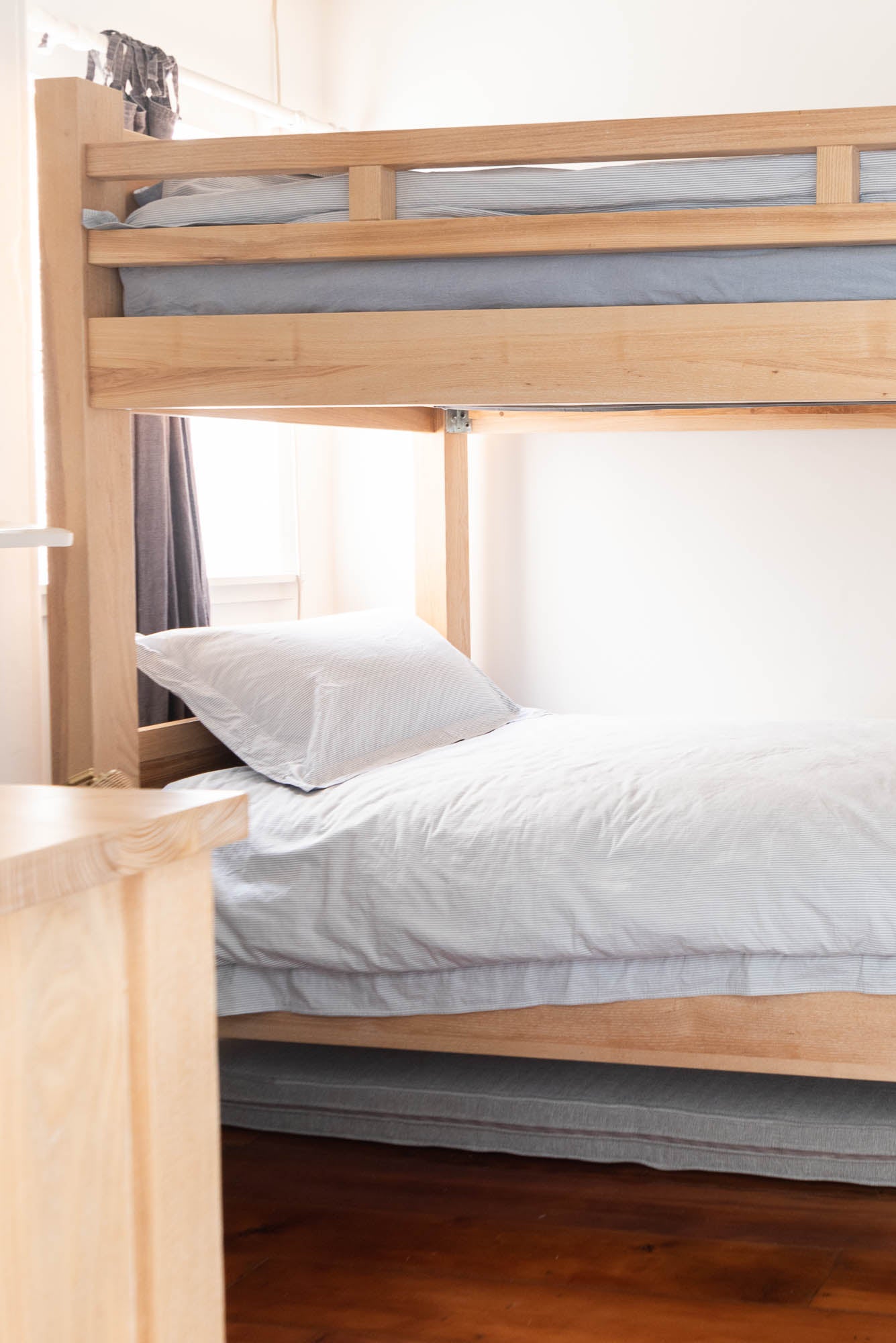 Wooden bunk bed with white bedding in a room setting