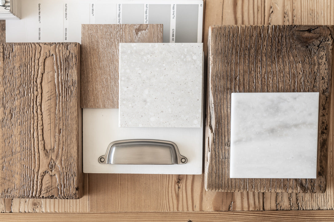 Wooden and marble sample boards with a metallic handle on a wooden surface.