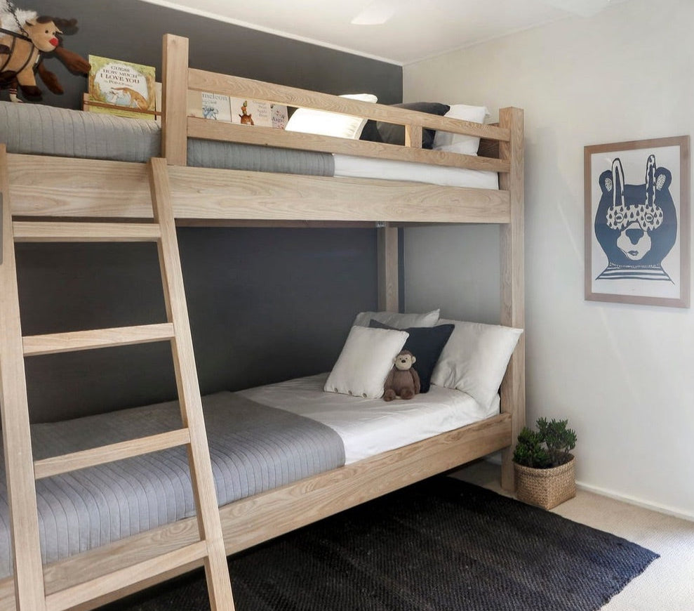 Wooden bunk bed in a room with a dark gray wall and a framed picture on the wall.