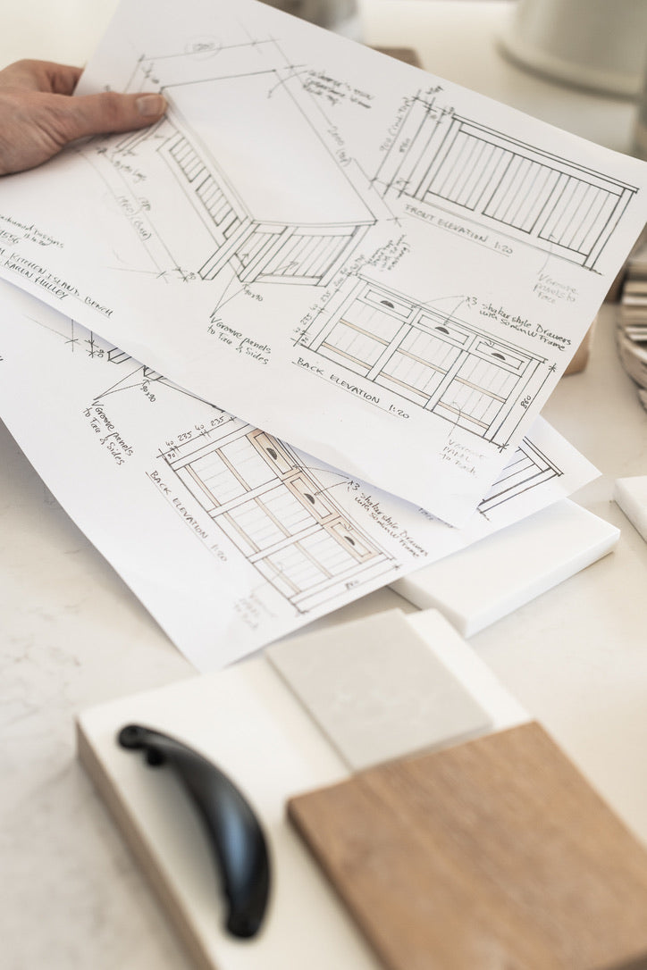 Blueprints on a table with a pen and notebook