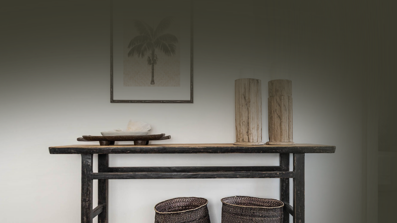 Wooden console table with decorative items against a plain wall.