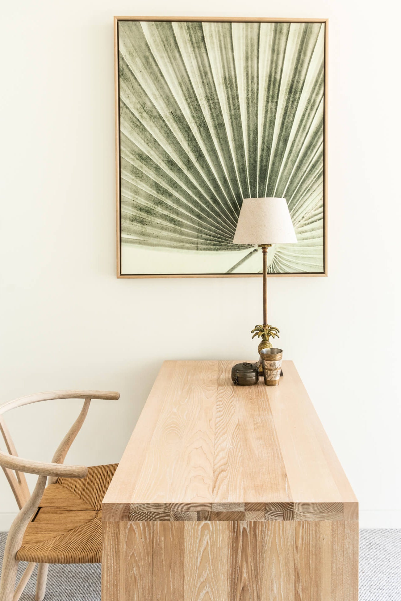 Wooden desk with a lamp and decorative items, framed artwork on the wall.