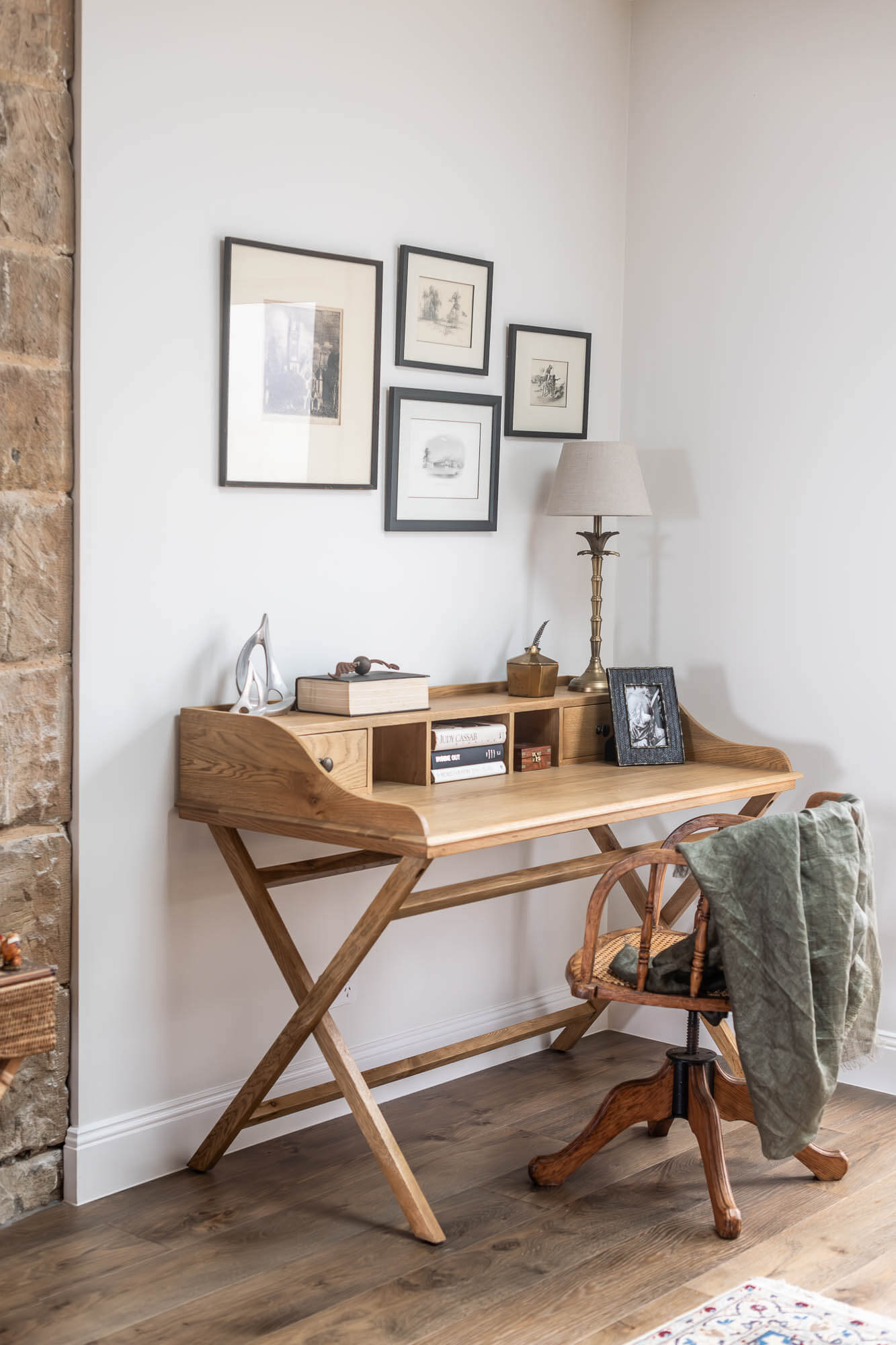 Wooden desk in a home office with framed pictures on the wall.