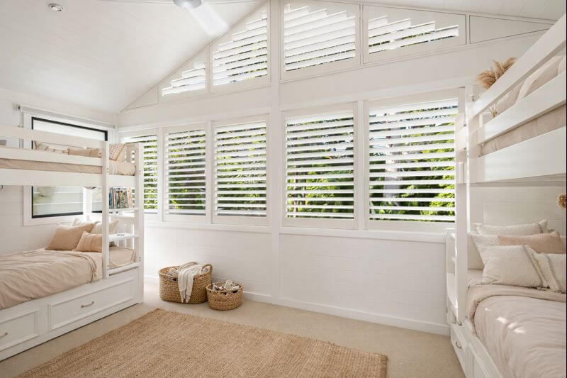 Children's bedroom with bunk beds and white shutters on the windows.