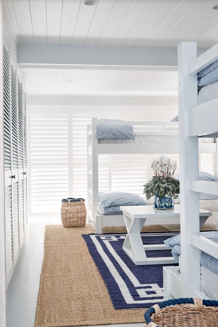 Children's room with bunk beds, table, and rug.