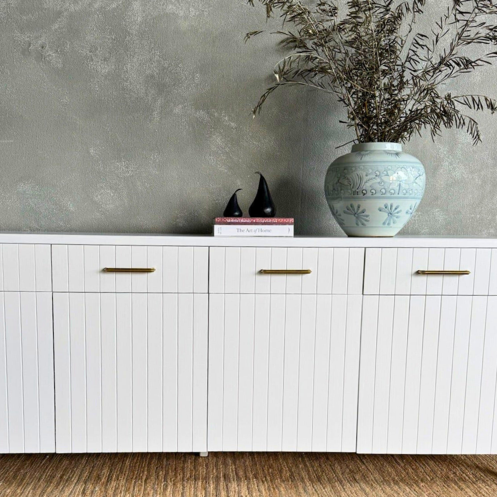 White cabinet with decorative items against a gray wall