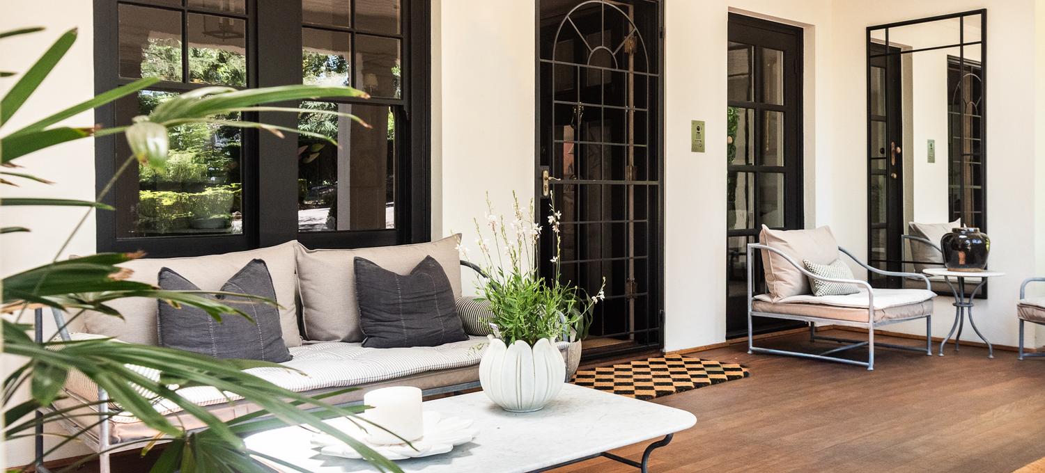 Modern living room with black-framed glass doors, white sofa, and decorative items.