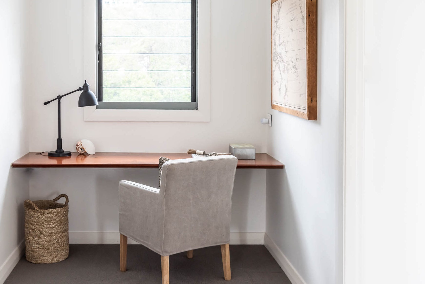 Home office with a wooden desk, chair, and lamp in a room with a window.